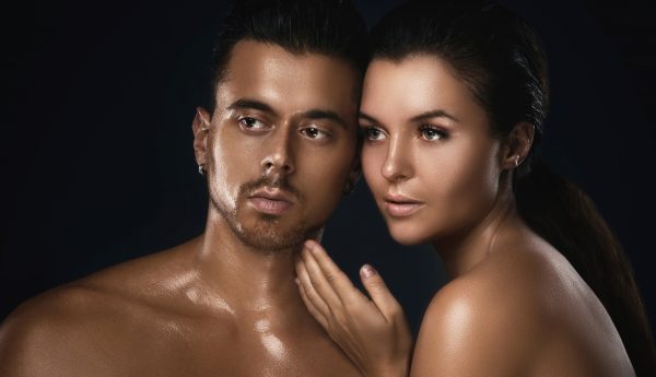 Portrait of young beautiful couple in studio on black background